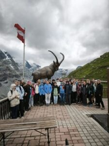 Steinbock-Denkmal am Gletscher mit Gruppe und österreichischer Fahne in den Alpen