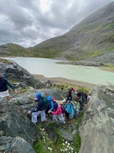 Kinder klettern in den österreichischen Alpen über Felsen zu einem Bergsee.